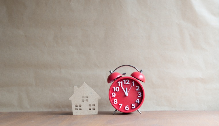 Miniature wooden house and black clock,Dream house,Real estate concept