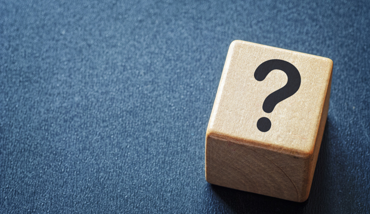 Wooden toy cube with a question mark viewed high angle on a textured blue background with copy space in a conceptual image