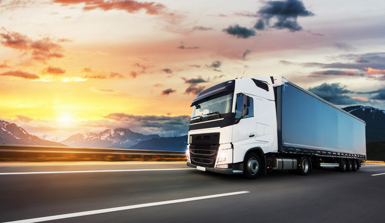 European truck vehicle on motorway with dramatic sunset light. Cargo transportation and supply theme.