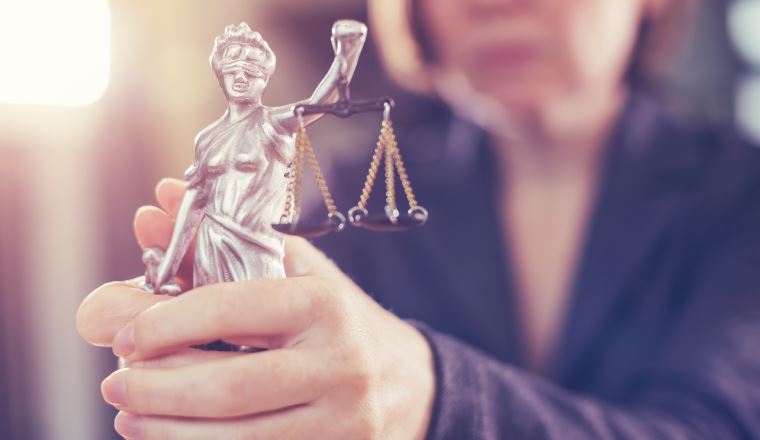 State attorney holding statue of Justice in office, selective focus