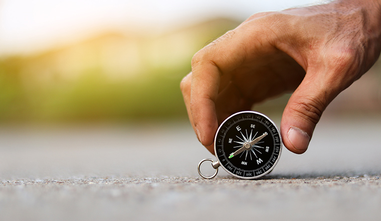 A man holding compass on road texture background, journey of life concept