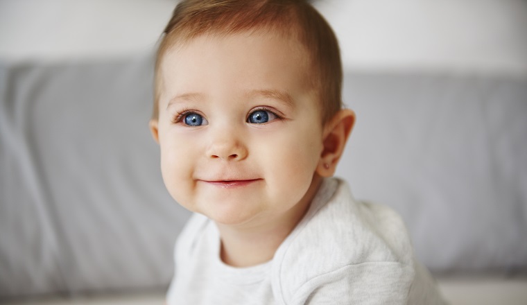 Close up of charming baby sitting on bed