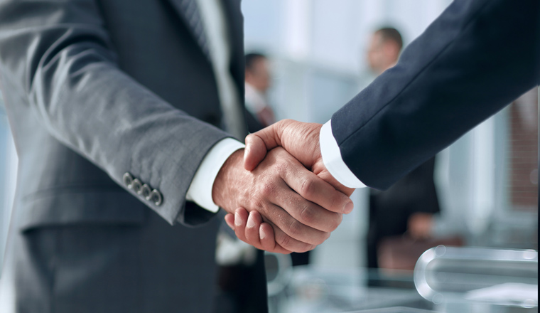 closeup of handshake of business partners on the background of business team