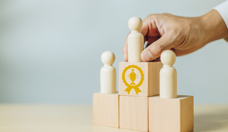 A man holding wood person model standing on award podium. Concept of leadership, success,winner and victory in business