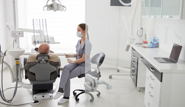 Portrait of young female dentist standing by mid adult man in clinic