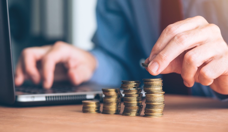 Finances and budgeting, businessman stacking coins on office desk