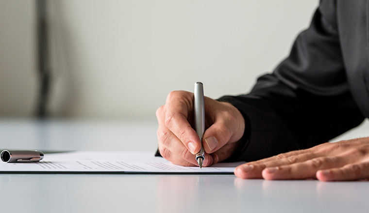 Wide panorama view of businessman hand signing legal or insurance document or business contract on white desk.