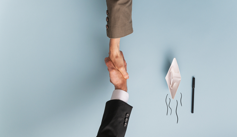 Top view of businessman and businesswoman shaking hands in agreement and collaboration. Over light blue background with paper made origami boat and copy space.