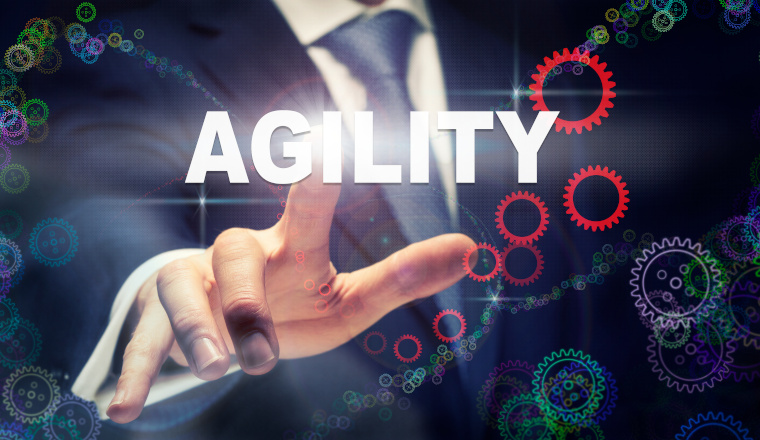 A businessman pressing a Agility business concept on a graphical display of cogs