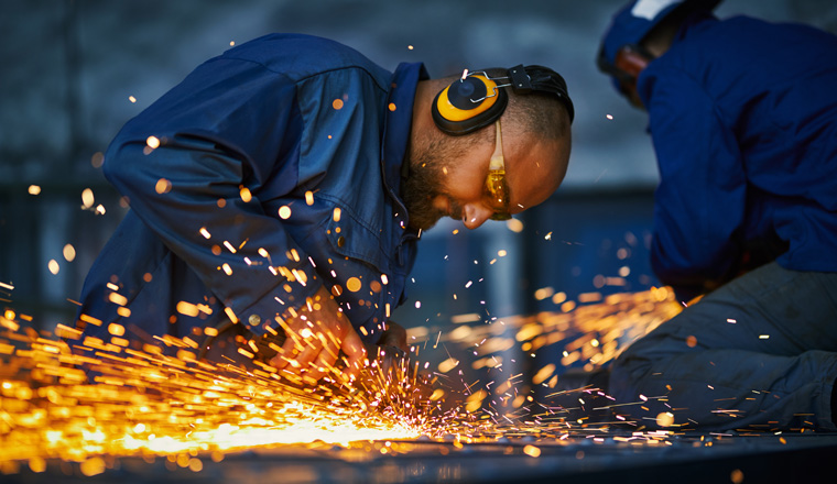 Group of two craftsmen in protective uniform welding metal construction. Spark from metalworking. Concept of people, industry and manufacture. 