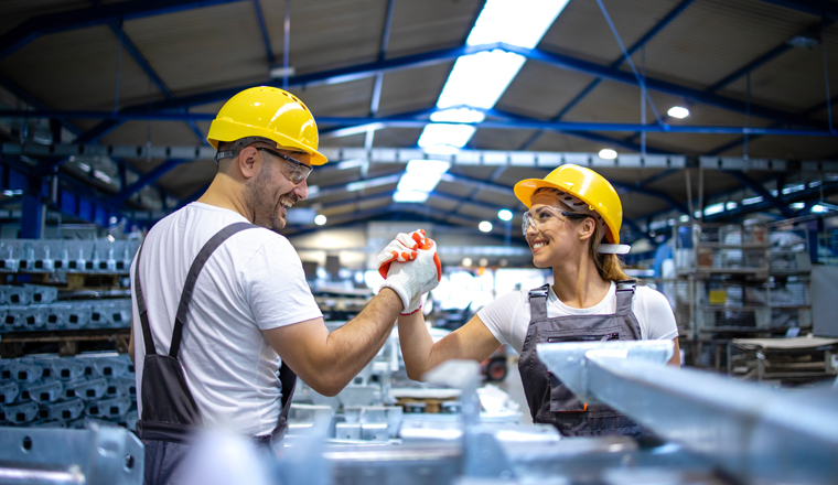 Factory workers handshaking each other at production line.