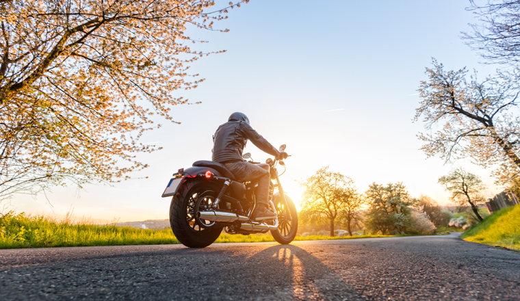Back view of motorcycle driver driving in beautiful sunset