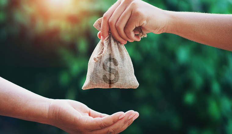 hand giving money bag to another people on green background with sunrise