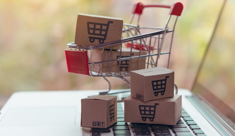 Shopping online concept - Parcel or Paper cartons with a shopping cart logo in a trolley on a laptop keyboard. Shopping service on The online web. offers home delivery.
