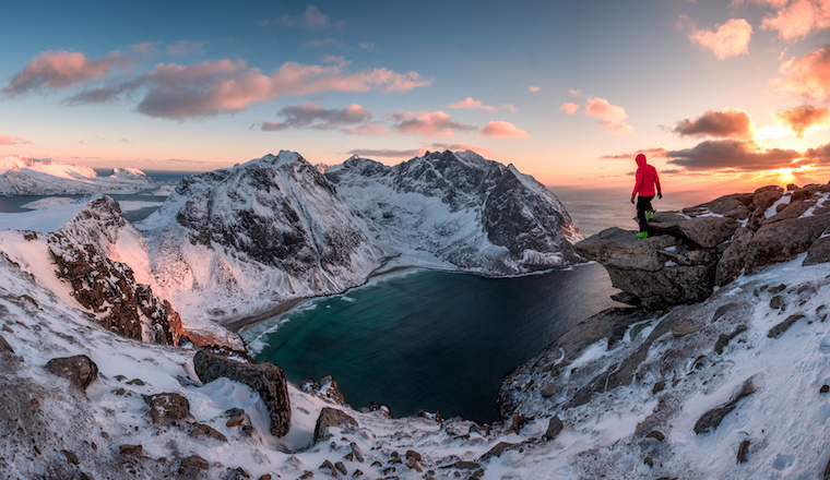 Man mountaineer standing on rock of peak mountain at sunset. Ryten Mountain, Norway