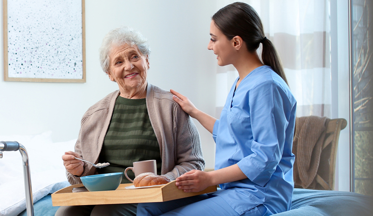 Care worker serving dinner for elderly woman on geriatric hospice. Banner design