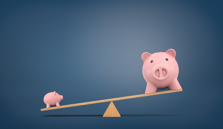 3d rendering of a wooden seesaw on chalkboard background with a small piggy bank overweighing a large one. Long-term value. True worth. Wealth comparison.