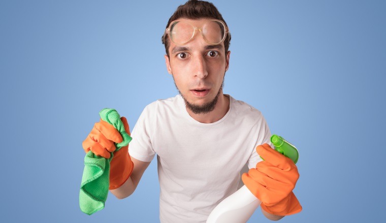 Housekeeper with cleaning product and equipment in front of a blue empty wall