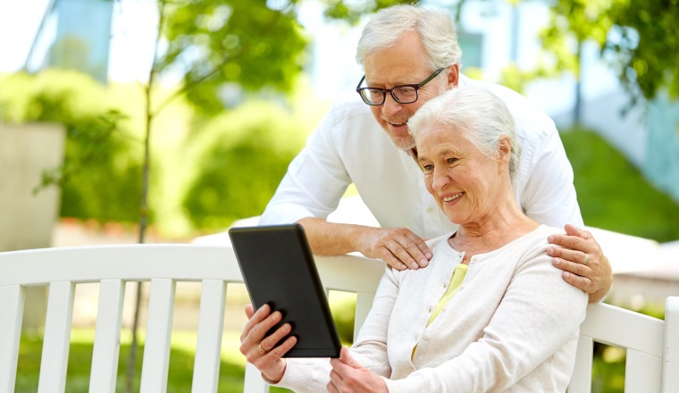 retirement, technology and old people concept - happy senior couple with tablet pc computer at summer park