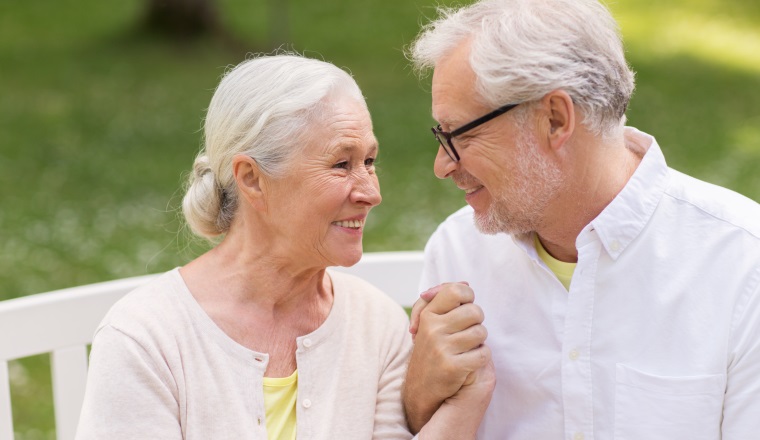 old age, relationship and people concept - happy senior couple sitting on bench at summer park