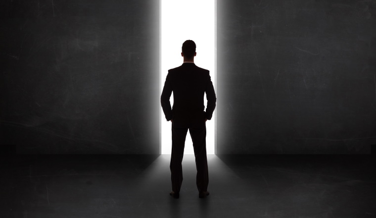 Business person looking at wall with light tunnel opening concept