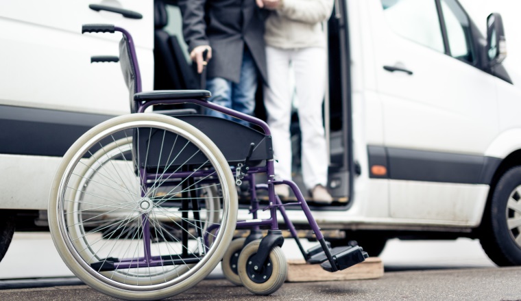 nurse helping senior man exit a van and get to his wheelchair