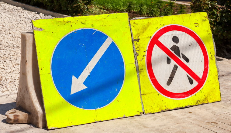 Road signs at the under construction sidewalk in summer day