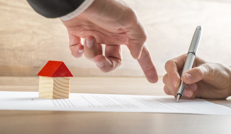 Closeup of real estate agent showing his client where to sign a contract of house sale or mortgage papers. Suitable for real estate concept.
