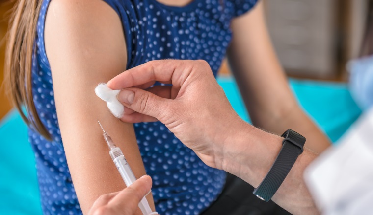 Pediatrics female doctor giving a young girl a vaccine shot in the arm