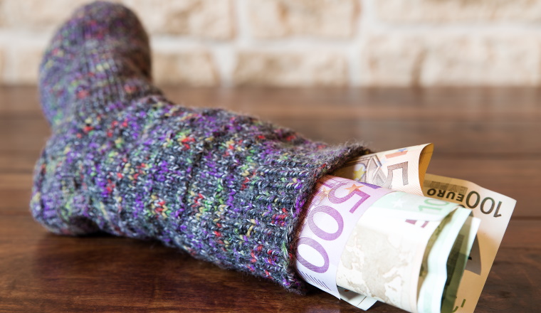 Sparstrumpf mit Euros auf Holztisch