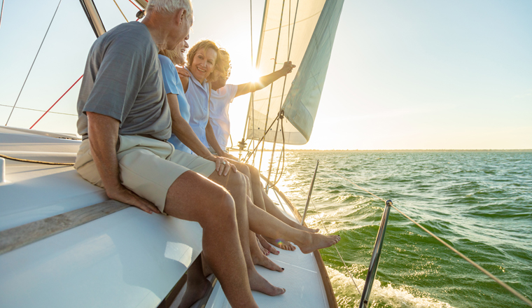 Relaxed group of senior American friends sailing towards horizon on luxury yacht enjoying freedom outdoors in retirement