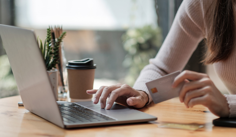 Close up of black girl hold bank credit card and type on laptop, shopping online using computer, buying goods or ordering online, entering bank accounts and details in online banking offer