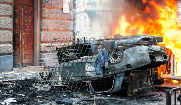 car destroyed and set on fire during the riots. city center. clouds of smoke