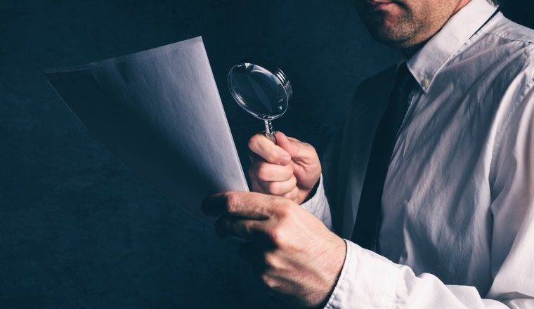 Tax inspector doing financial auditing, businessman reading business report or contract footnotes disclaimer with magnifying glass, retro toned, selective focus