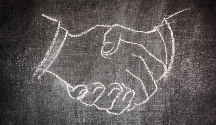 business deal handshake illustrated on a blackboard in white chalk scratched