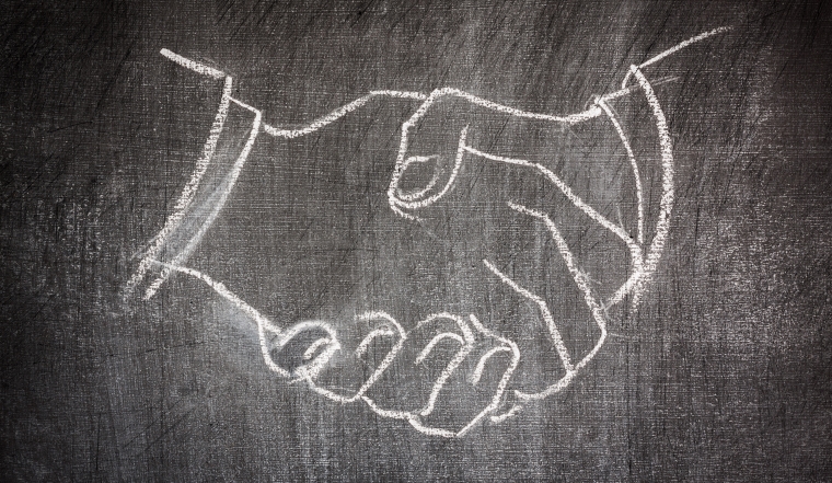 business deal handshake illustrated on a blackboard in white chalk scratched