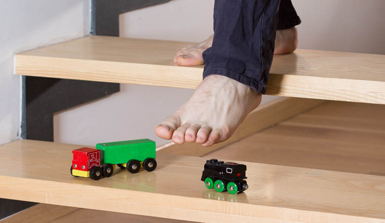 Close-up of man's foot stepping on toys on stairs