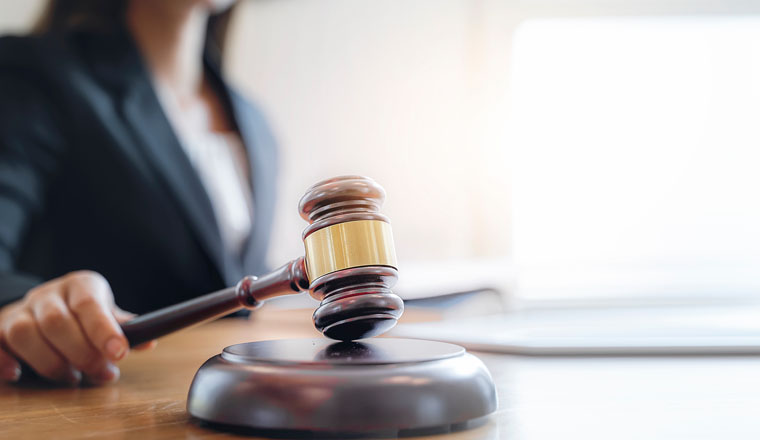 Woman judge hand holding gavel to bang on sounding block in the court room.