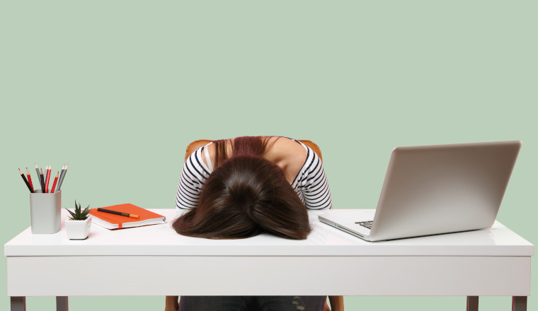 Young frustrated exhausted woman laid her head down on the table sit work at white desk with contemporary pc laptop isolated on pastel pink background. Achievement business career concept. Copy space