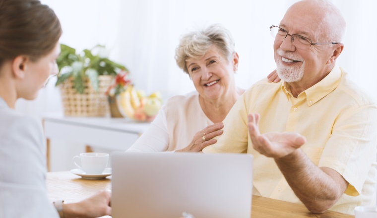 Young insurance agent with smiling couple showing an offer on the laptop