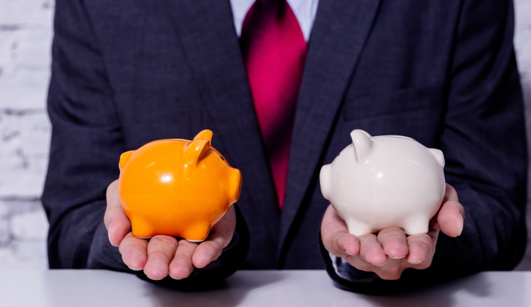 Businessman making a comparison and difference between each money piggy bank - finance issue comparison concept