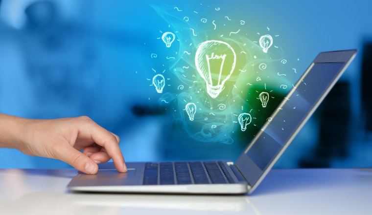 Close up of hand with laptop and glowing idea bulb