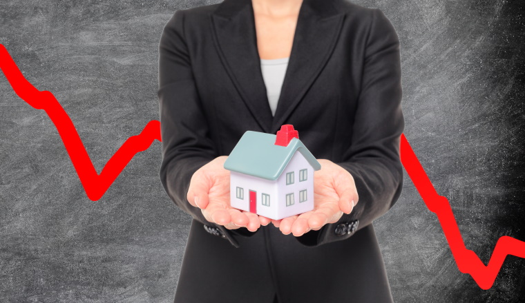 Real estate market crash due to recession economic downturn from coronavirus pandemic crisis. Realtor showing miniature home on red graph blackboard.