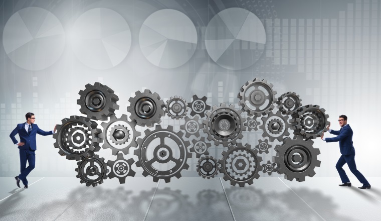 Businessman pushing cog wheels in business concept