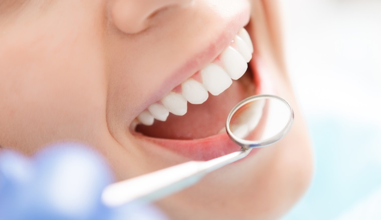 Doing professionally. Smiling pretty woman is having her teeth examined by dentist in clinic.