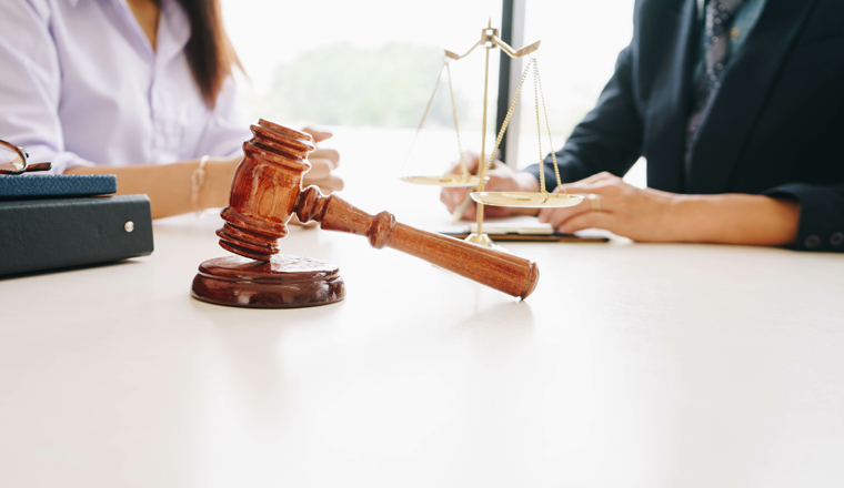 Businesswoman and male lawyers having a meeting at a law firm. Judge gavel and Gold brass balance scale. Legal law, lawyer, advice and justice concept.