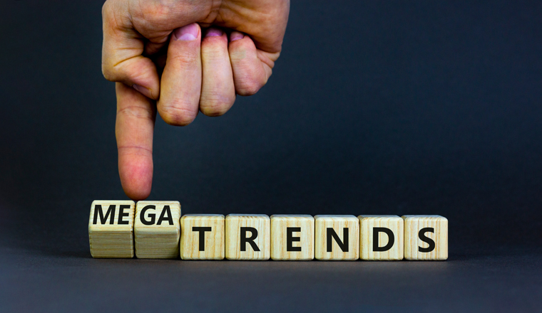 Trends or megatrends symbol. Businessman turns cubes and changes words trends to megatrends. Beautiful grey table, grey background, copy space. Business and trends or megatrends concept.