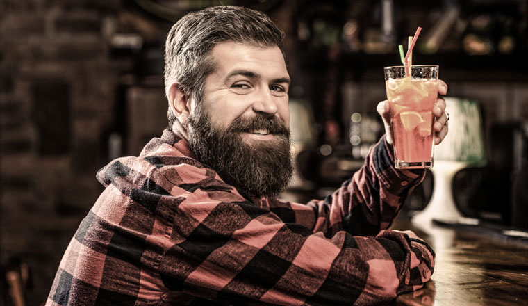 Bearded man cocktail. Portrait man, drinking orange juice. Barman in pub or restaurant. Cheerful bearded man, drink cocktails and smile. Tropical alcoholic fresh cocktail.