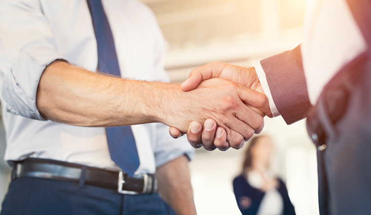 Businessmen shaking hands during a meeting. Closeup of business handshake between two colleagues in a modern office. Successful businessmen handshaking closing a deal. Agreement and business concept.