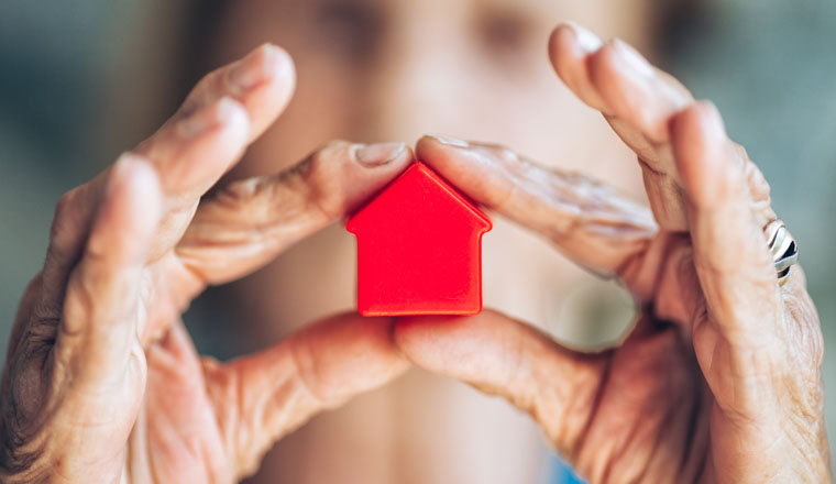 Elderly woman holding a small house in her hands